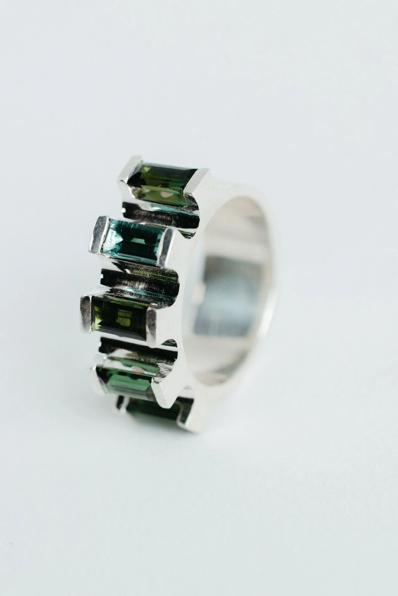 Engrenages ring V4.3 by Sajfrt — silver or gold sprocket-form ring with green or pink tourmalines. Handcrafted in Belgium with precise movement.
