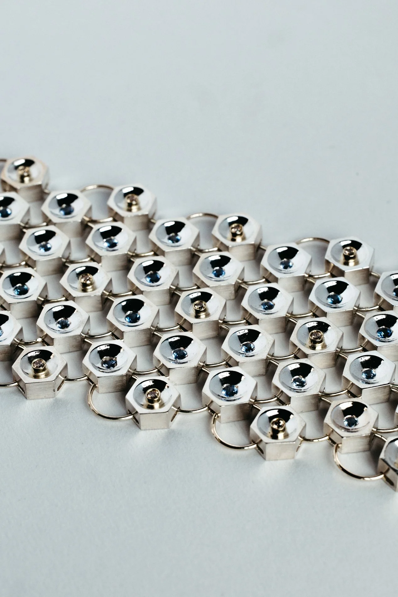 Silver and gold bracelet V1.1 from the Particles family — hexagonal forms with sapphires and salt & pepper diamonds, handcrafted by Sajfrt in Brussels.