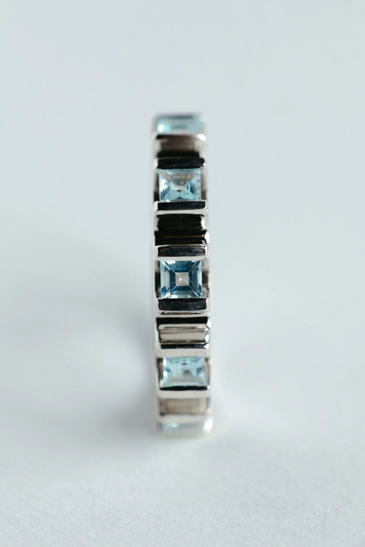 Engrenages ring V4.1 by Sajfrt — sprocket-inspired silver or gold ring with aquamarines or tourmalines. Handcrafted in Belgium with quiet geometry.