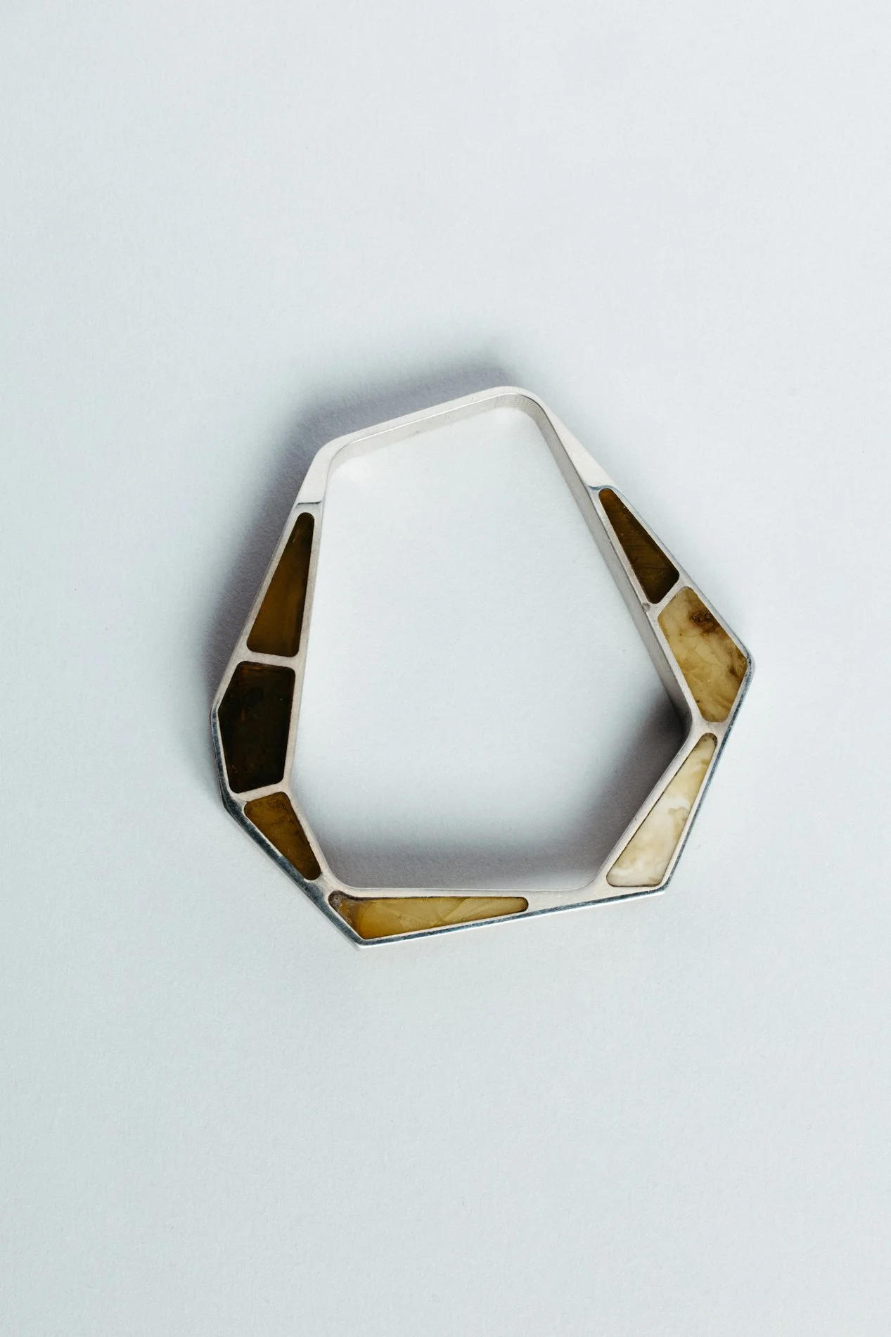 Engrenages bracelet V1.1 by Sajfrt — closed interlocking form in silver or gold with amber stone. Handcrafted in Belgium with architectural intent.
