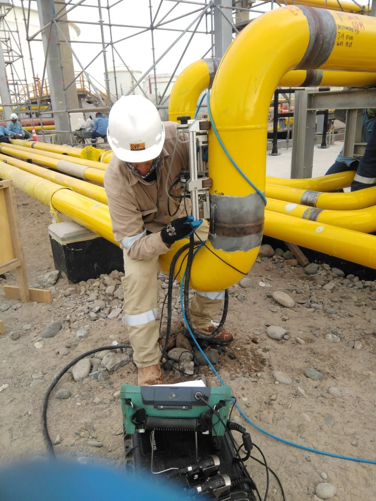 Trabajador en un sitio industrial ajustando una tubería amarilla.