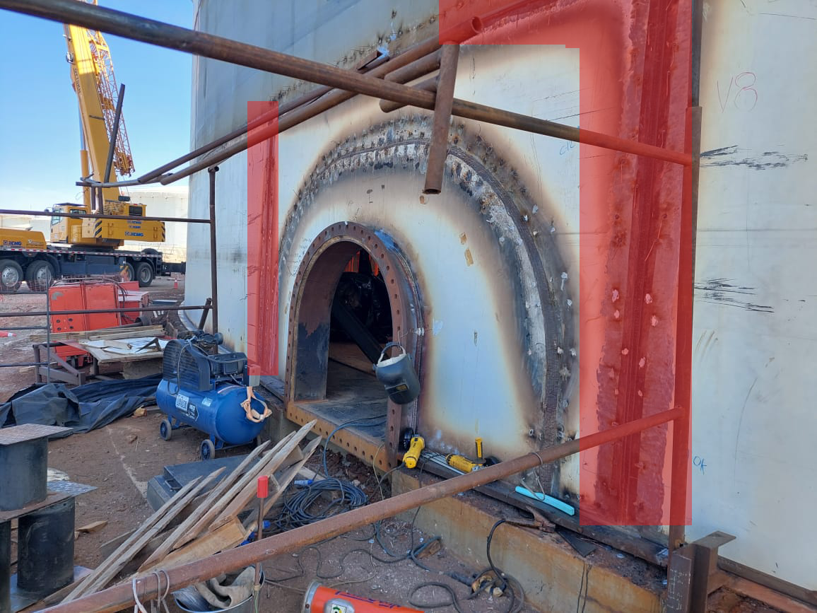 Escenario de construcción con un gran agujero en una pared, maquinaria y herramientas dispersas, y un andamio alrededor, en un sitio de obra