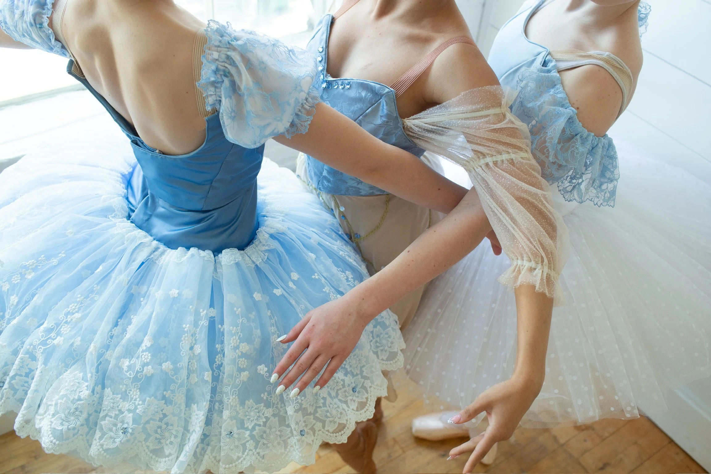Three ballet students showcasing the intricacies and creative details of their custom ballet costumes worn at professional ballet competitions.
