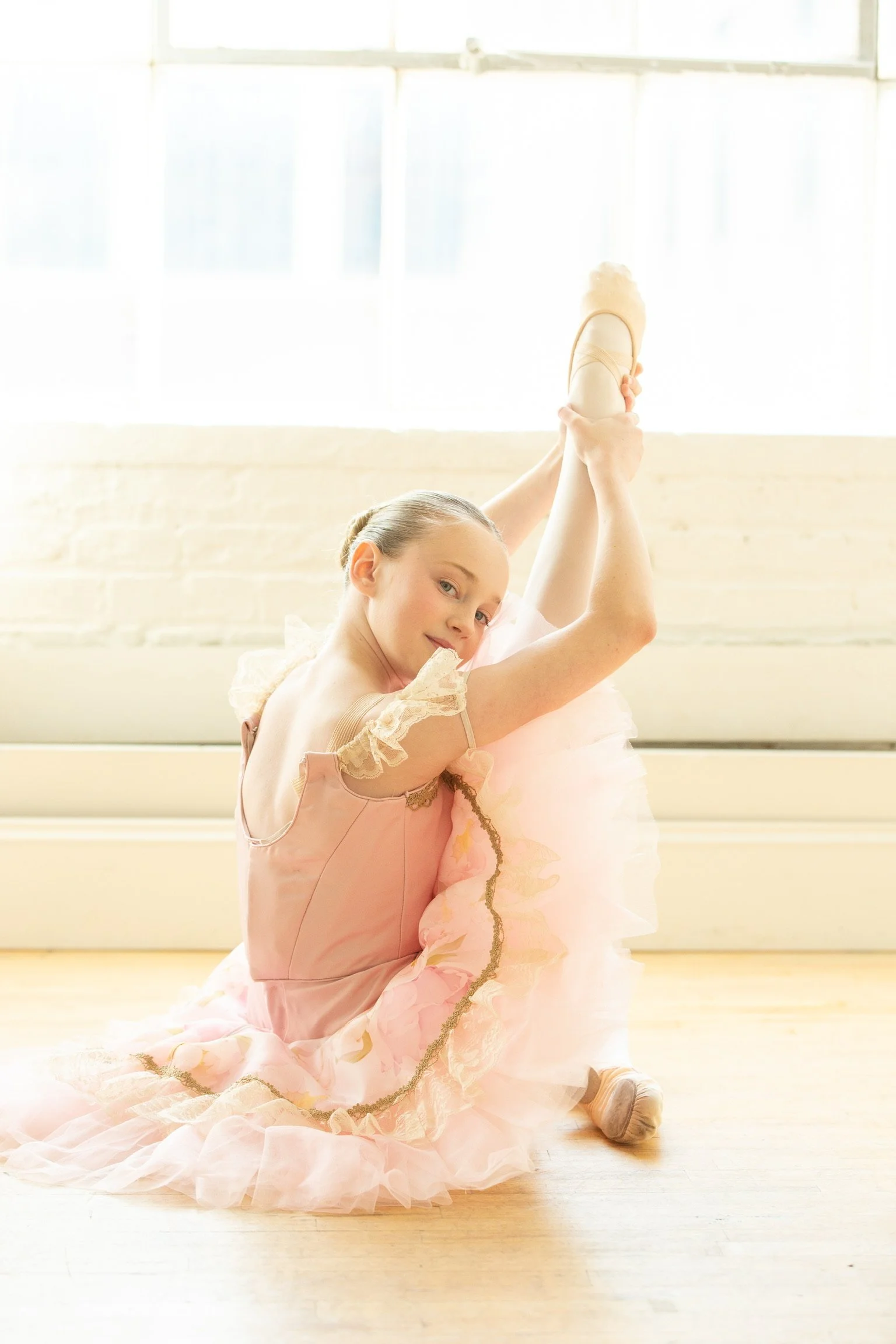 Le Chaton Tutu model wearing a pink tutu with ivory drape sleeves and an intricate tutu plate. 
