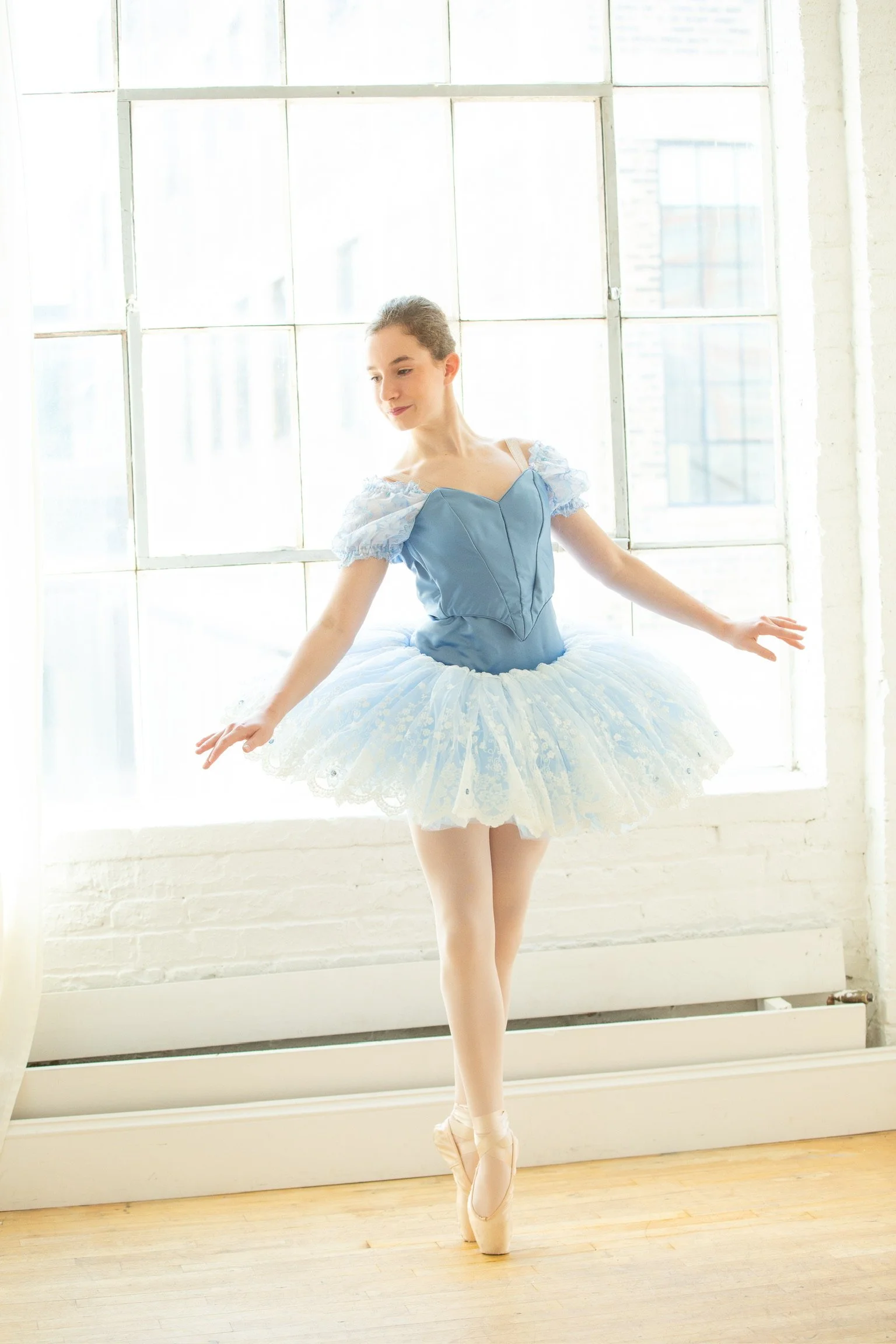 A ballet student showcasing her custom designed ballet costume featuring a lace plate, and floral sleeves, and sparkles in the skirt. This costume is perfect for competing professional ballet variations in various ballet competitions. 
