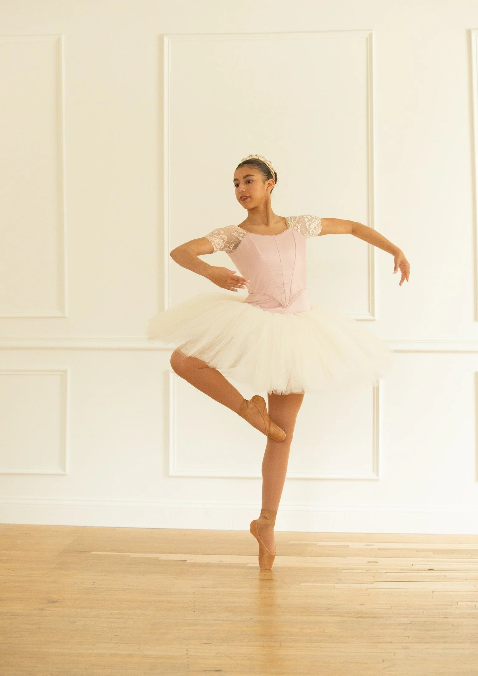Ballet student practicing poses in a fitted basque style bodice and tight stretch sleeves. 