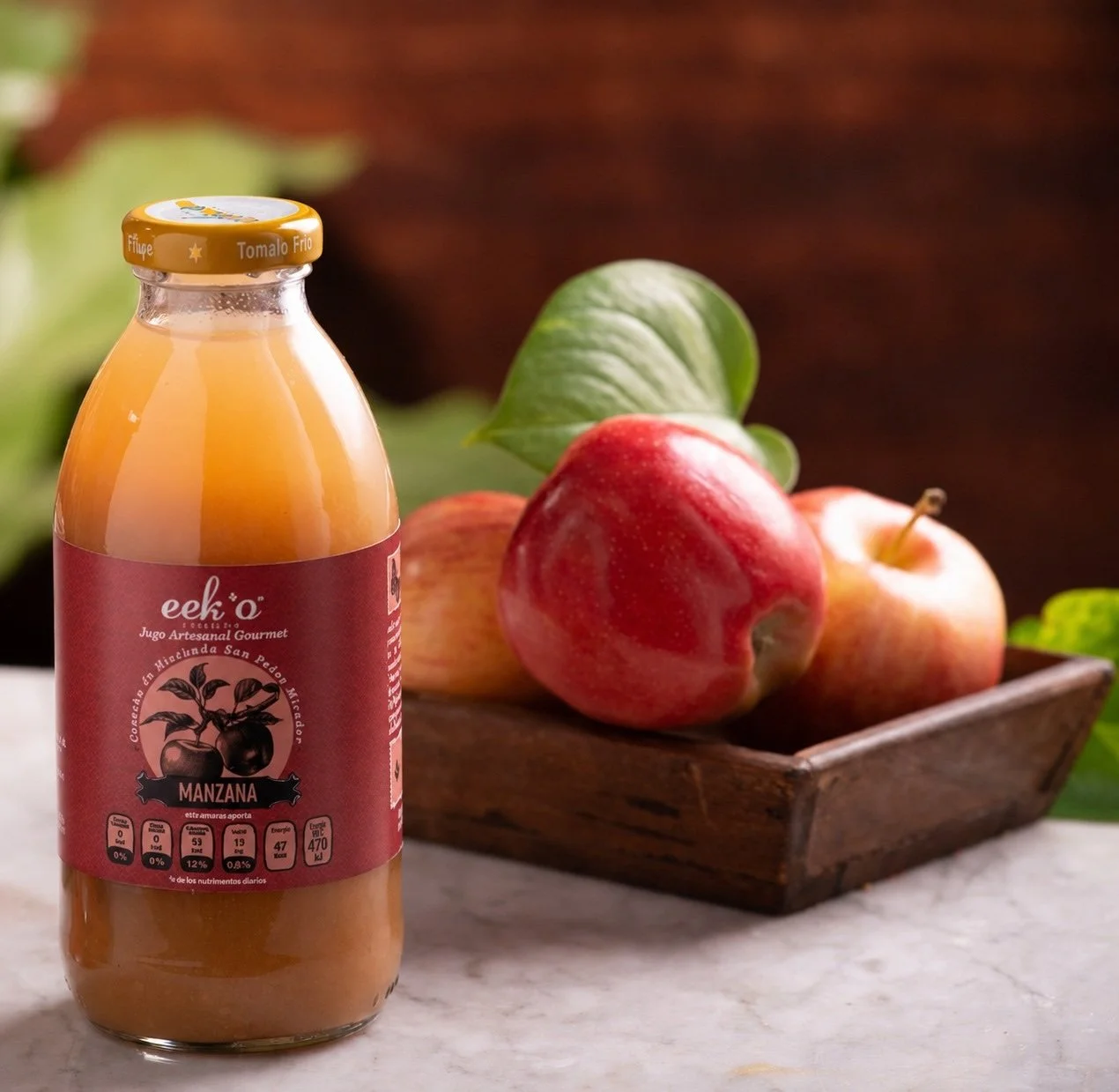 Botella de jugo de manzana junto a una tabla de madera con piezas enteras de la misma fruta