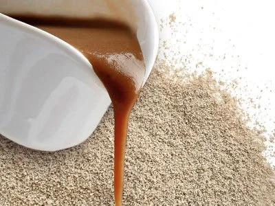 A white jug pouring foodies Classic Rich Gravy onto a bed of dry  foodies Classic Rich Gravy mix.