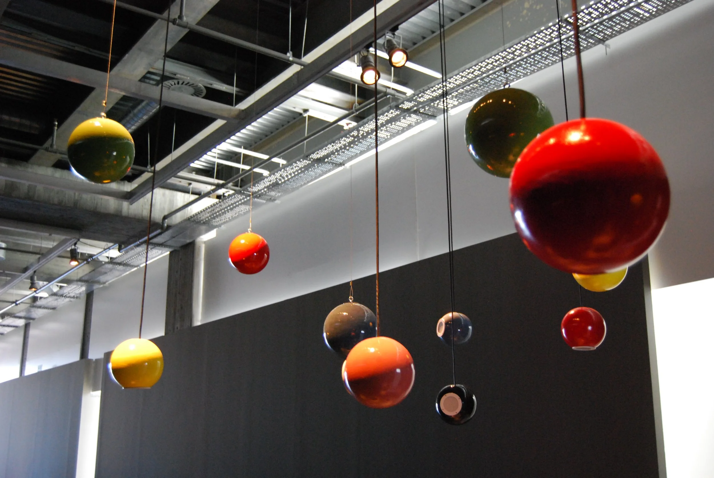 Hanging colorful spherical objects in a modern industrial interior space with exposed ceiling and lighting.