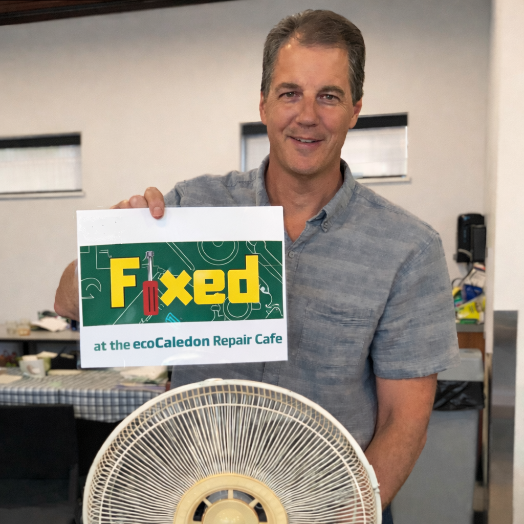 Headshot of STEVE HALLER, ecoCaledon director, smiing and holding up a "Fixed" sign at an ecoCaledon repair café event