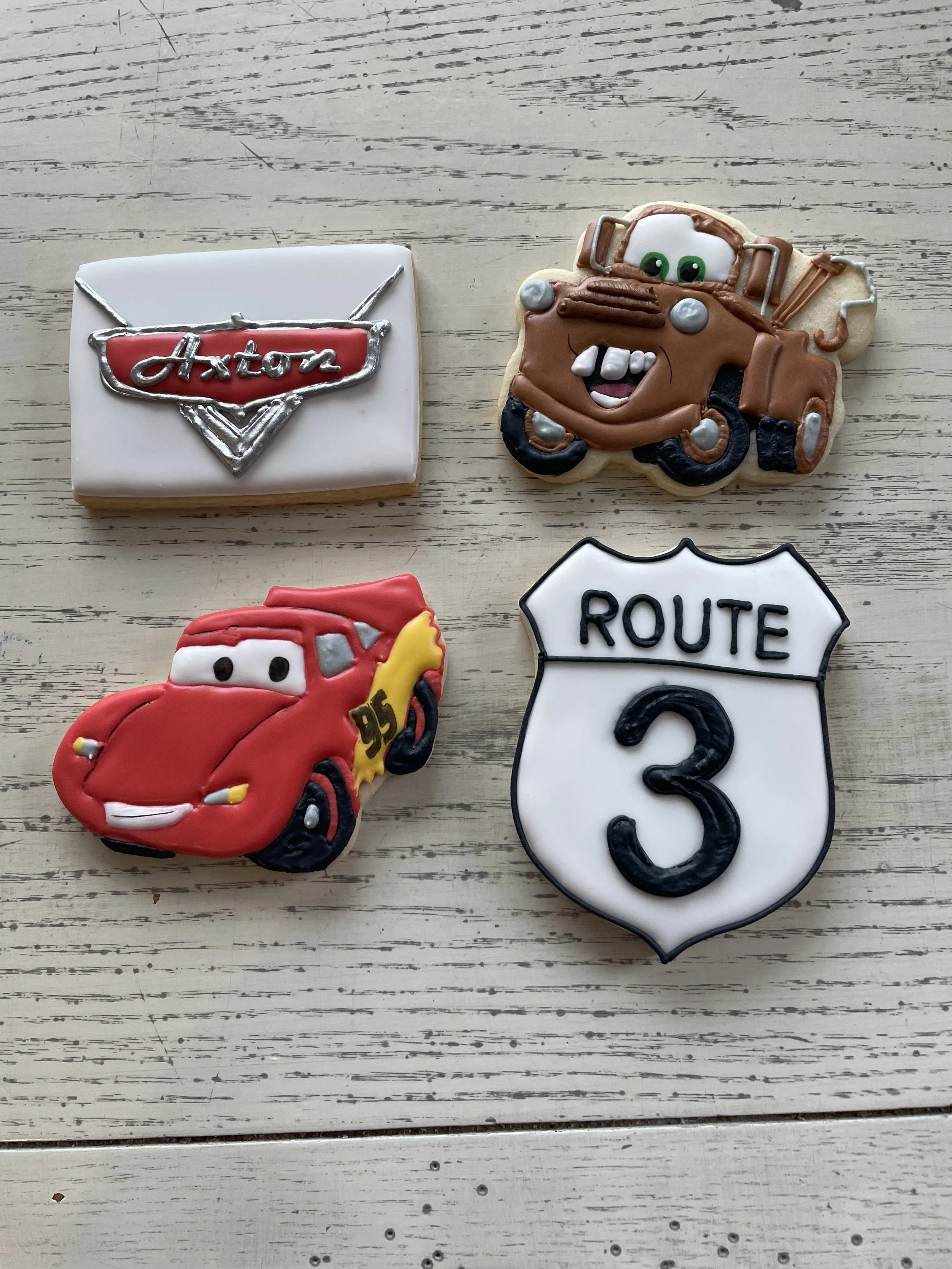 Decorated cookies of Lightning McQueen from Cars, Tow Mater, a Route 3 sign, and a box with an 'Austin' badge.