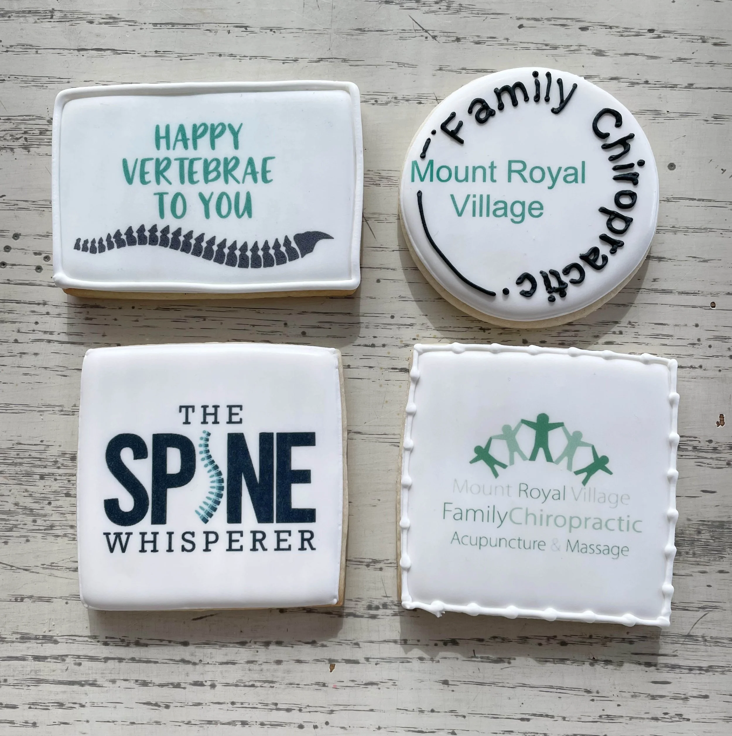 Four decorative cookies with text and images related to Mount Royal Village and chiropractic care, on a wooden surface.