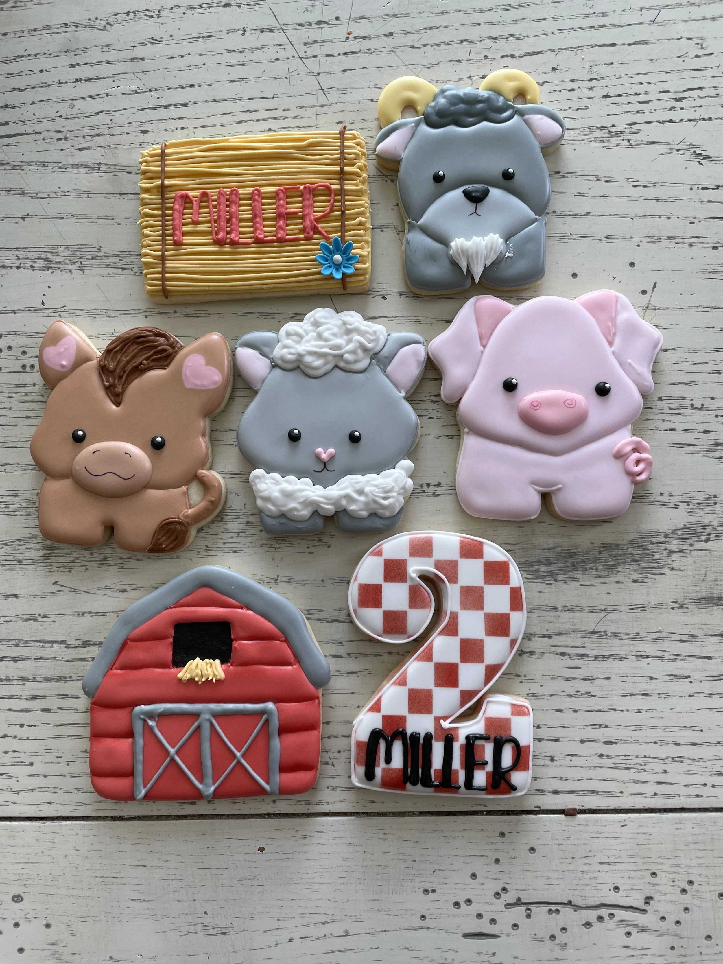 Decorated cookies featuring farm animals, a barn, and a number two celebrating a birthday, with the name 'MULLER' on some cookies.