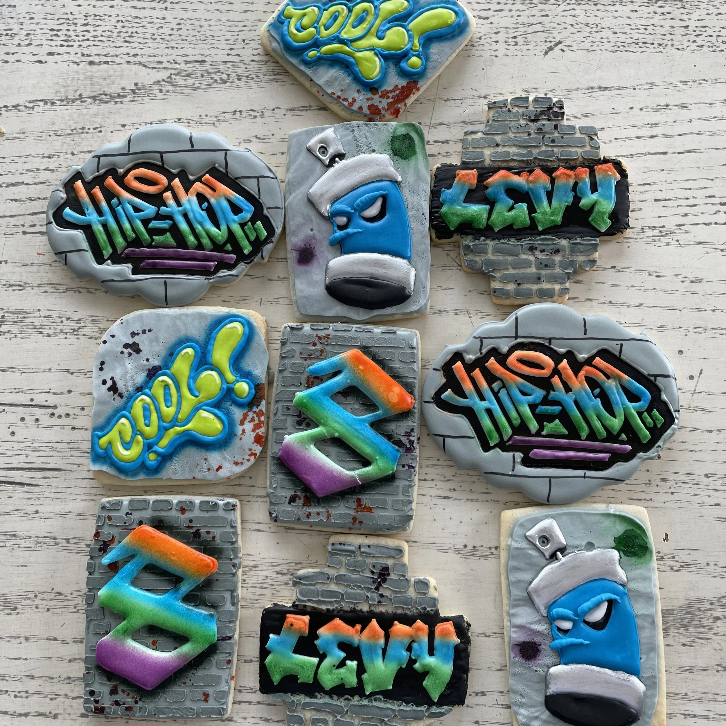 Decorative cookies with graffiti-style designs featuring words like 'TOO?!', 'LEVEL', 'HYPHOP!', and 'COOL?!', some with brick wall and spray paint backgrounds.