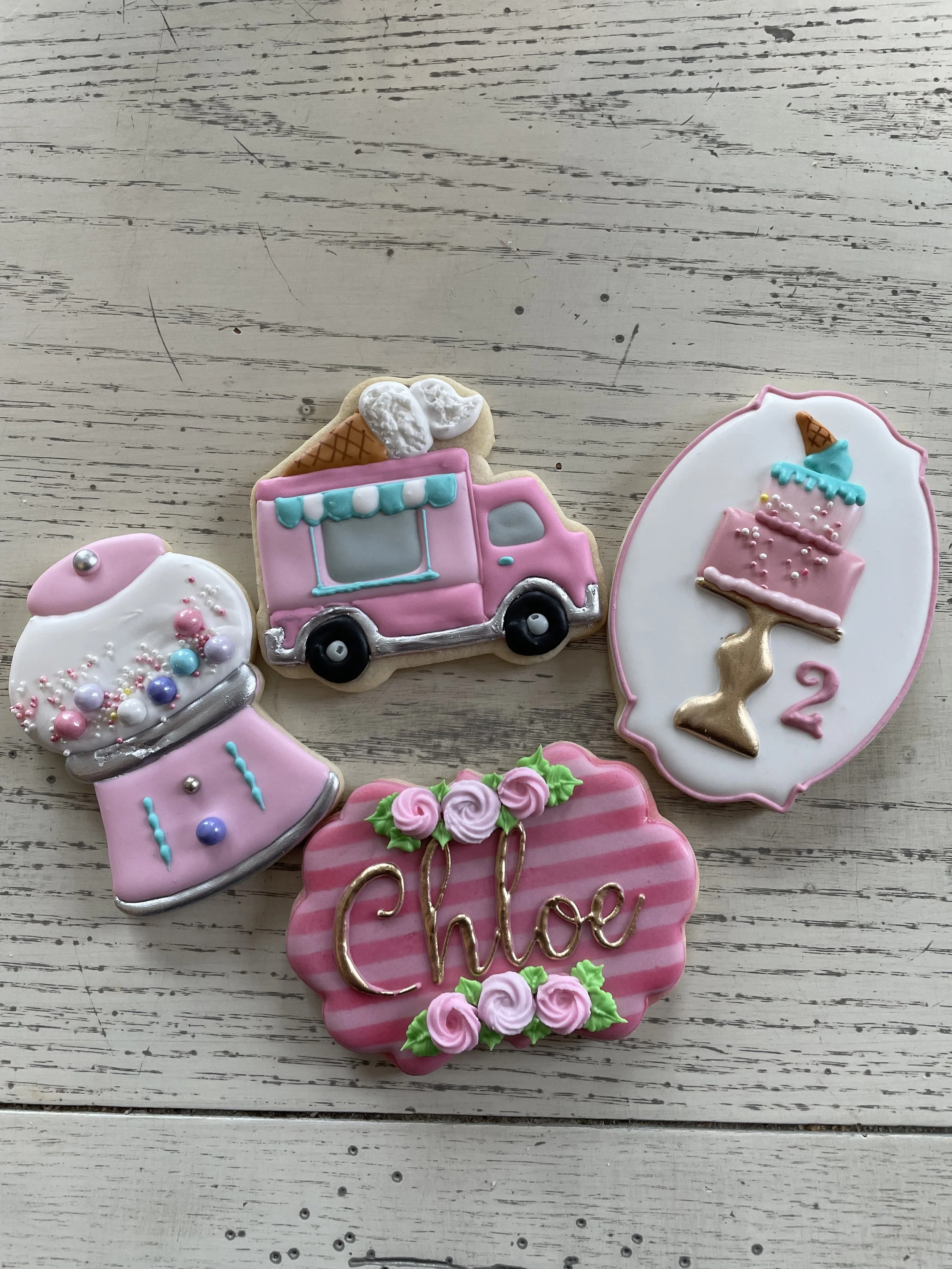 Decorative cookies with ice cream, ice cream truck, birthday cake, and the word 'Chloe' with pink roses.