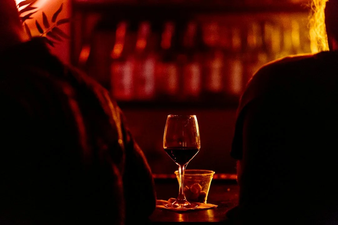A nearly empty wine glass against a dark bar background.
