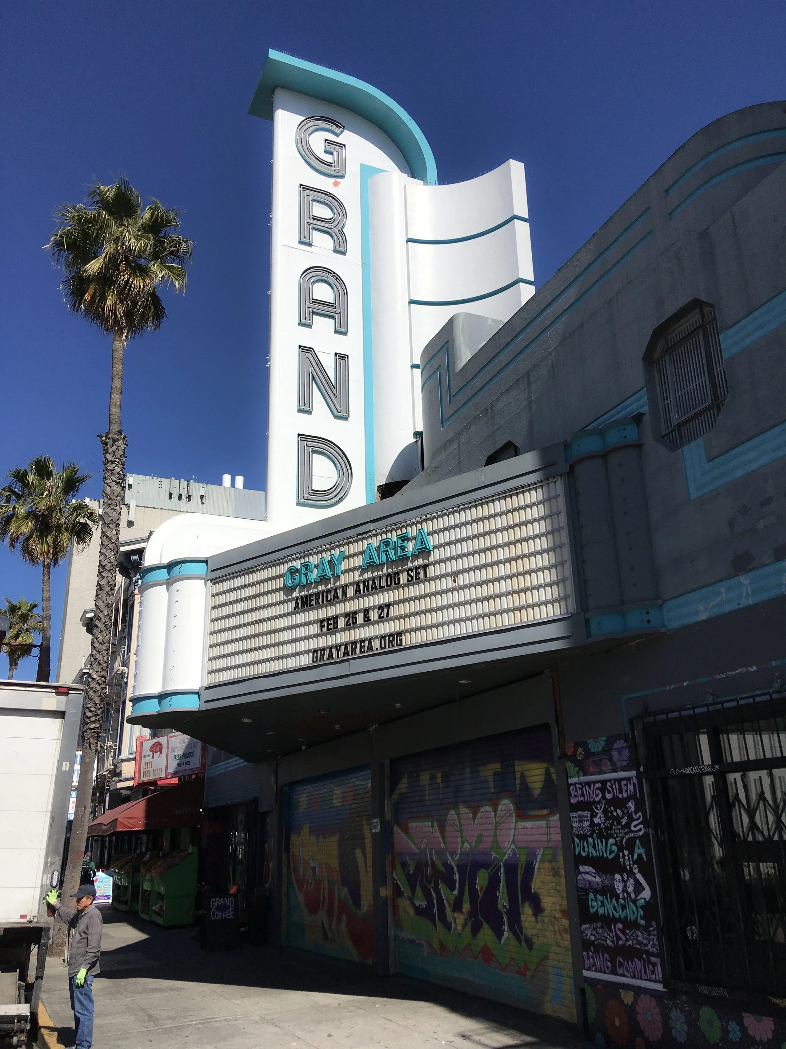 The white-and-teal Grand Theater facade and vertical GRAND sign on Mission Street in San Francisco.