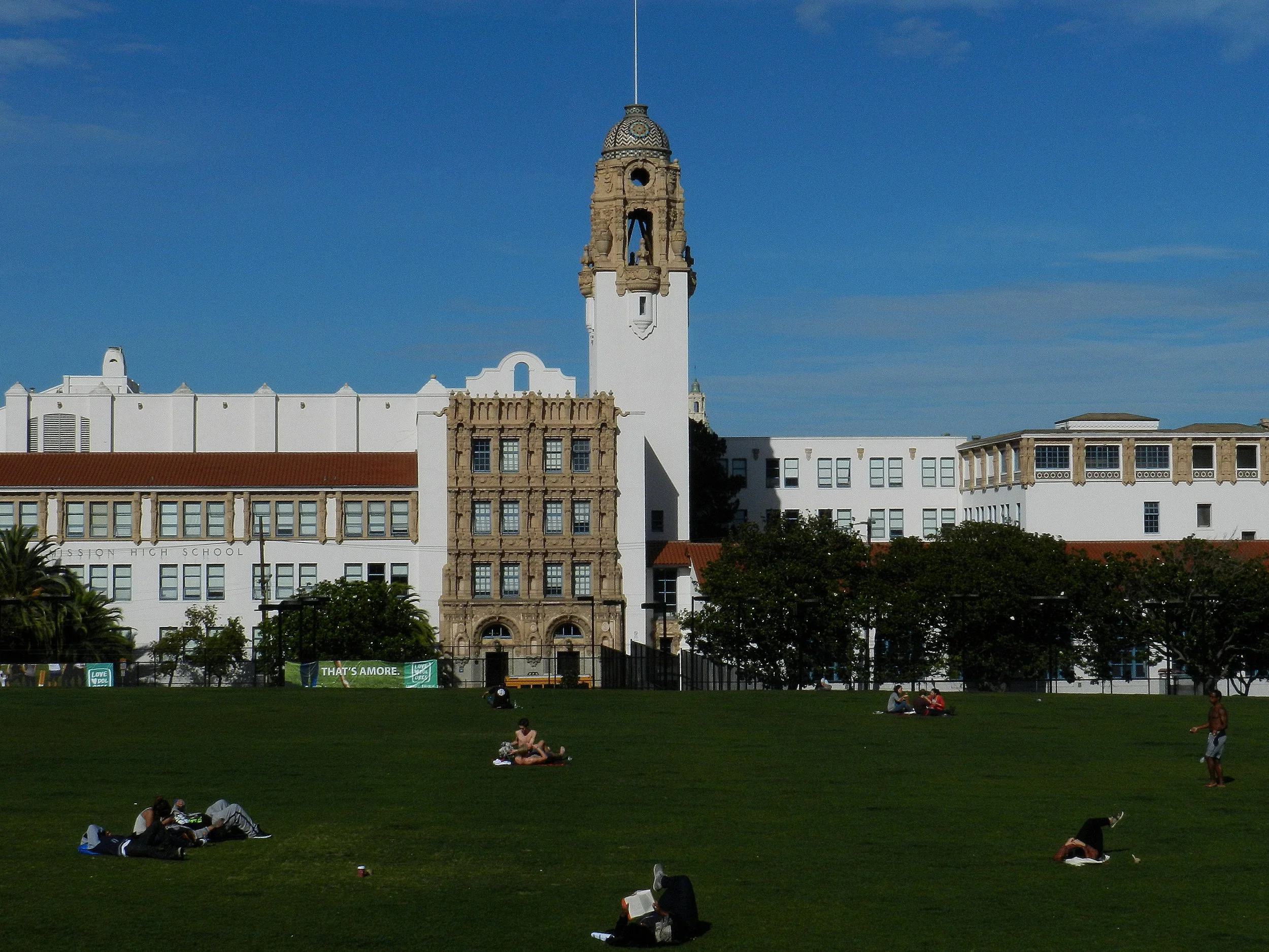 Green lawns and palm trees at Dolores Park with Mission High School in San Francisco.