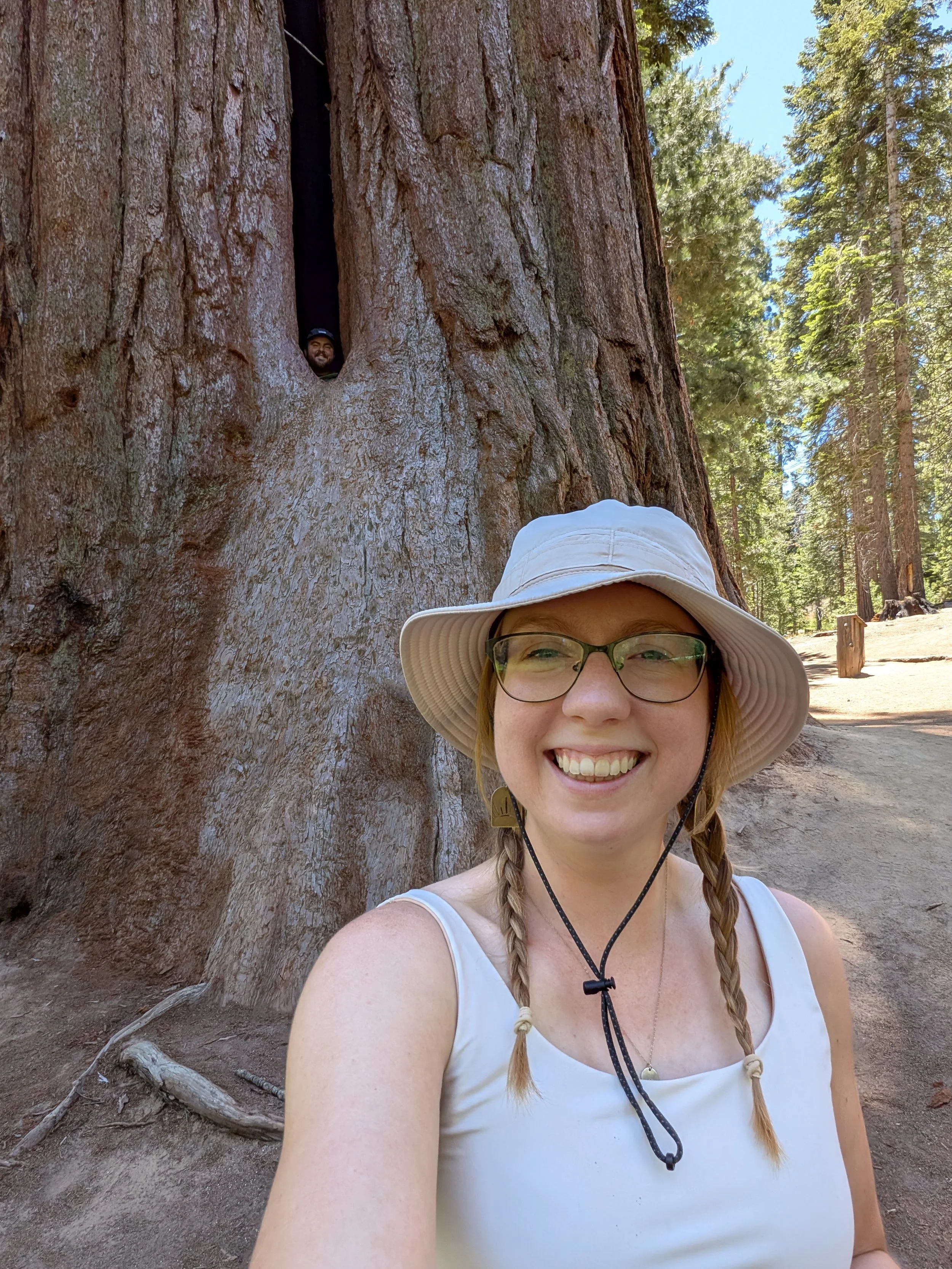 Lexi smiling for a selfie in front of a HUGE tree.