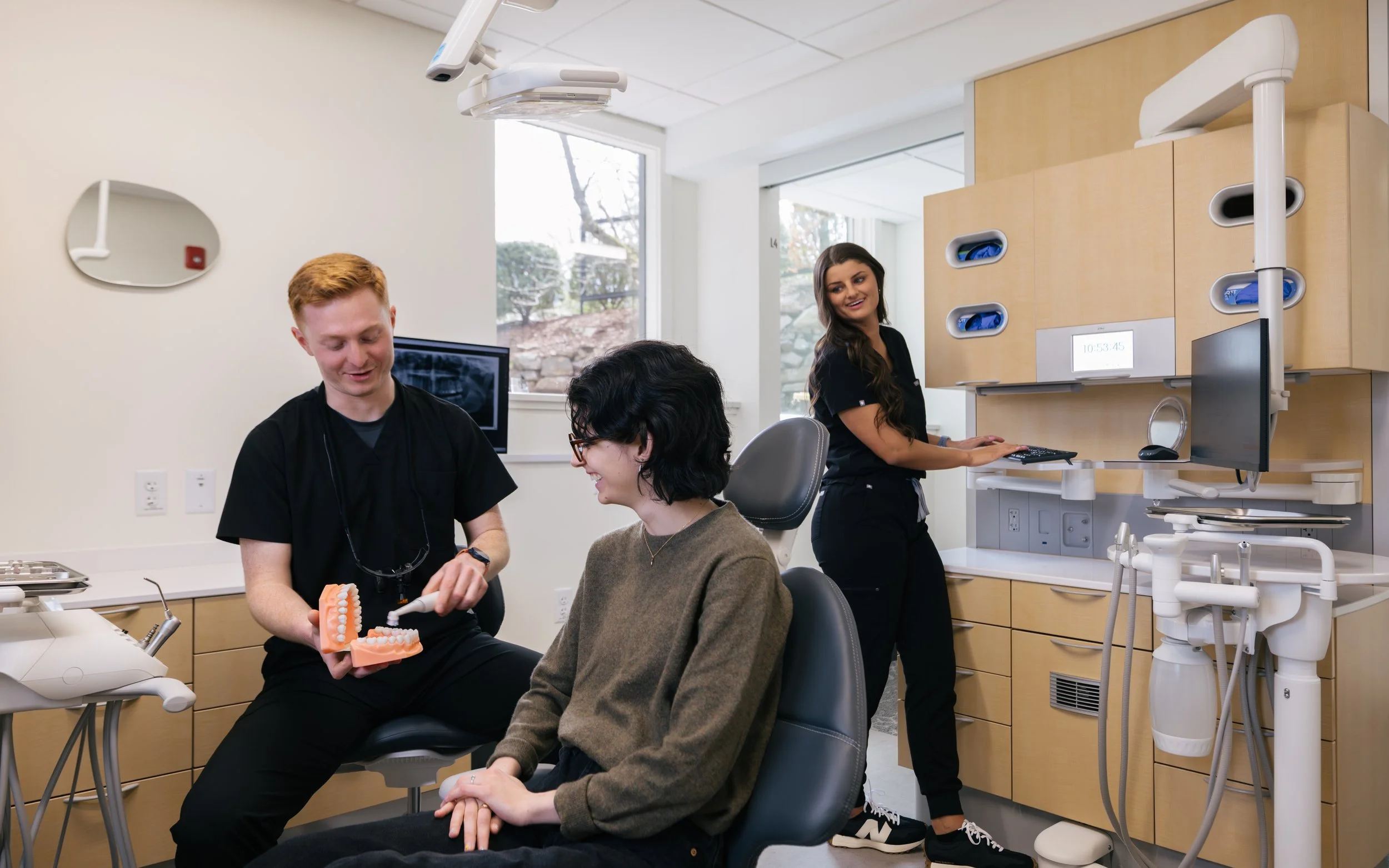 Dentist walking patient through general dentistry and cosmetic dental procedure in a warm and modern dental office environment