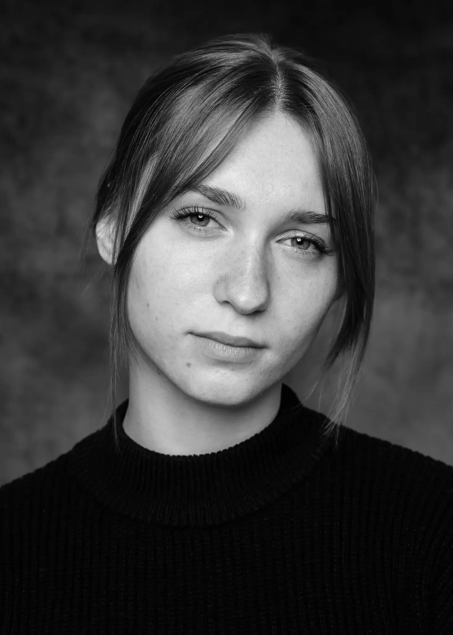 Schwarz-weiß Porträt einer jungen Frau mit kurzen, hellbraunen Haaren und hellem Teint, trägt einen schwarzen Pullover.