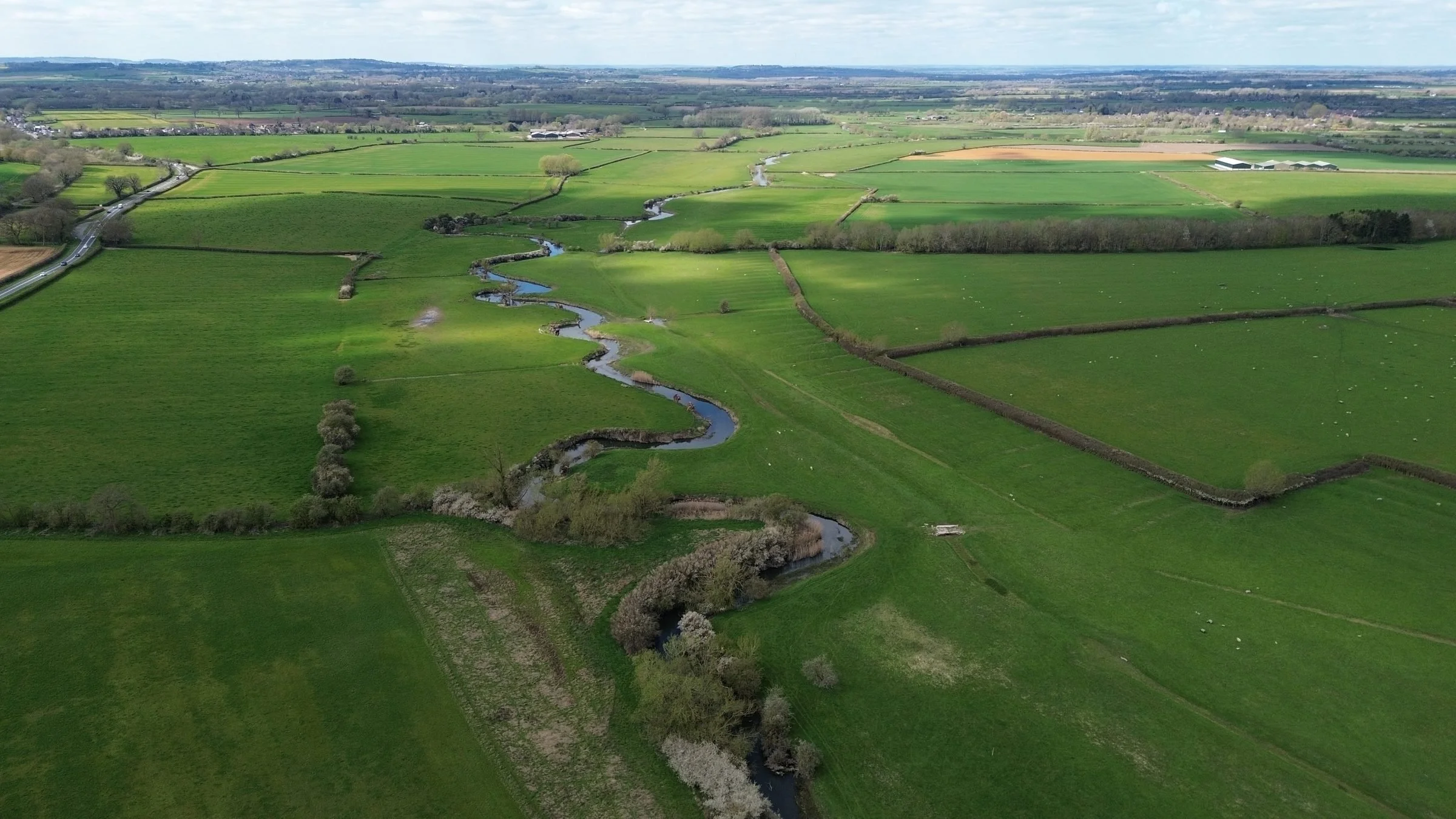 Aerial view of the River Thame winding through fields at Rycote Farm habitat bank, South Oxfordshire
