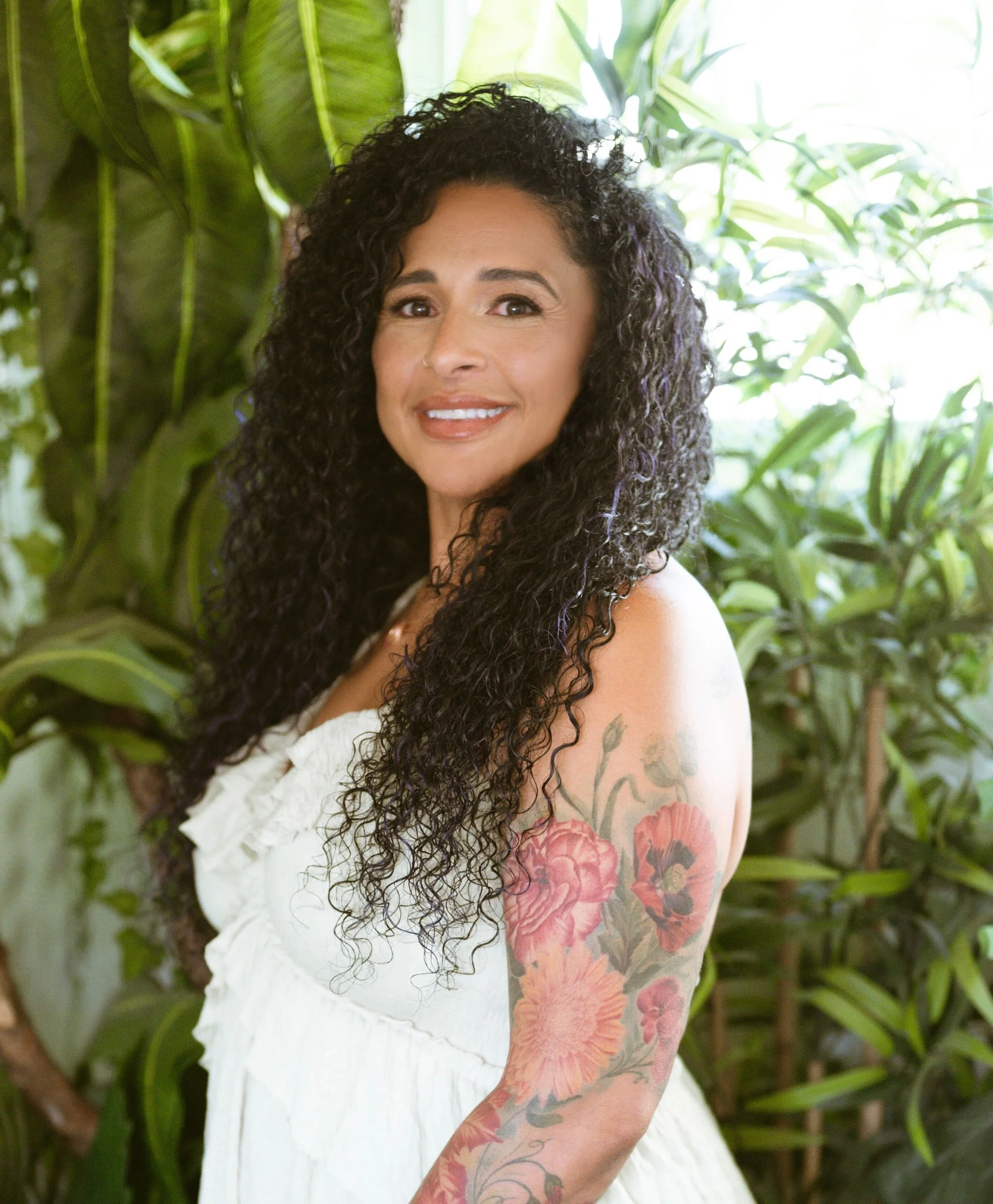 A woman wearing a cowboy hat and a denim top, smiling.