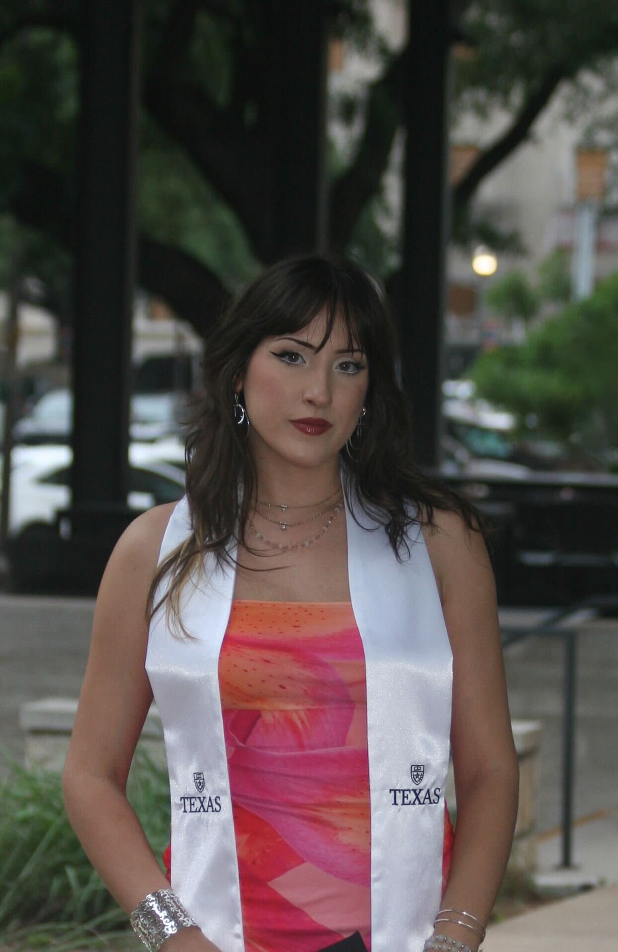 A person with long, brown hair, wearing an orange and pink dress