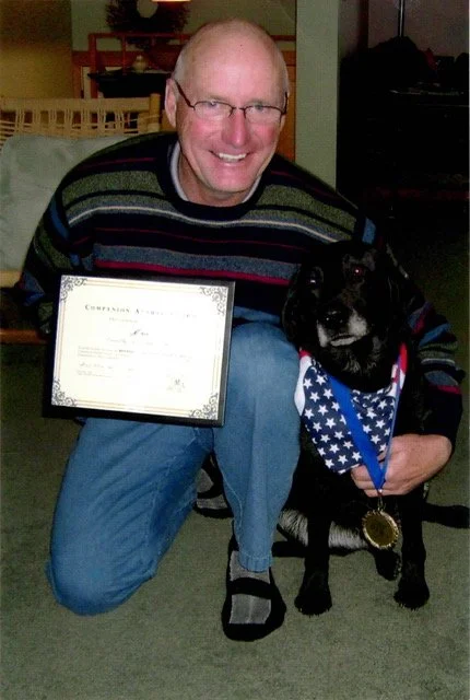 Tim and his service dog Milly with her award from the VA