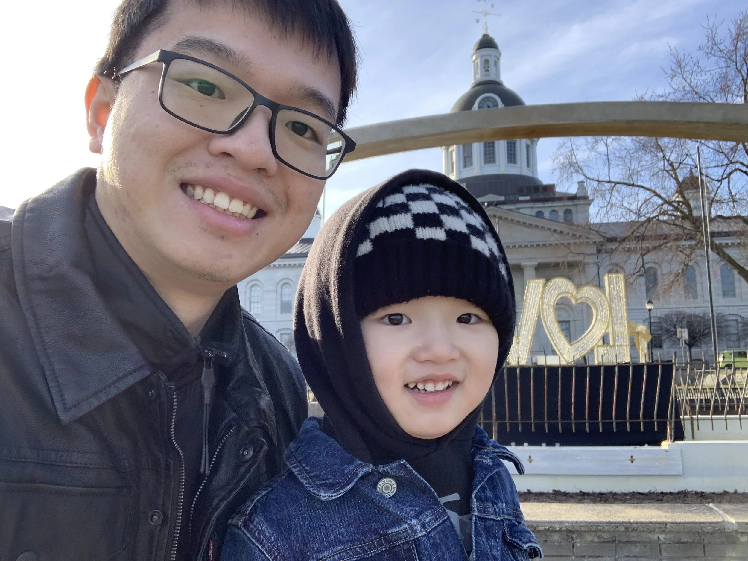 Two people smiling with a historic building and heart sculpture in the background.