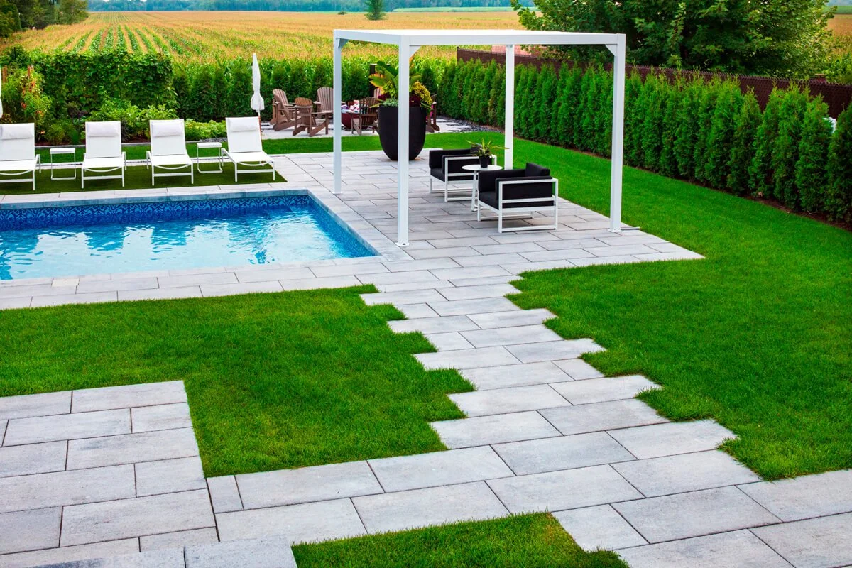 Backyard with a swimming pool, lounge chairs, modern pergola, seating area, and green lawn.