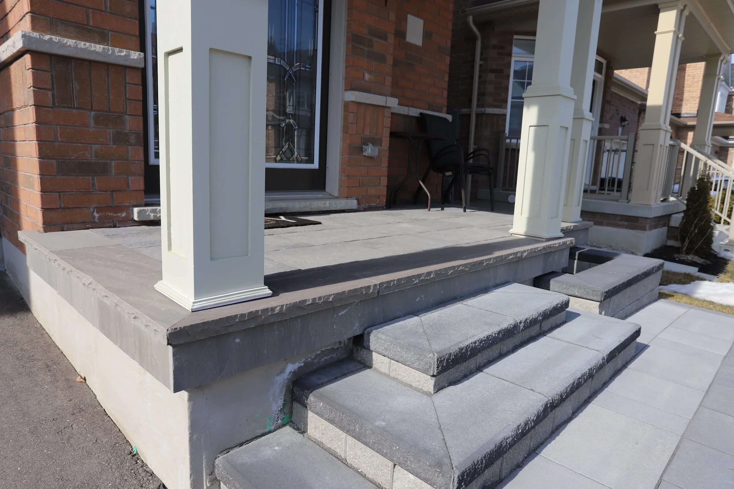 Front porch with stone steps, brick siding, and white columns.