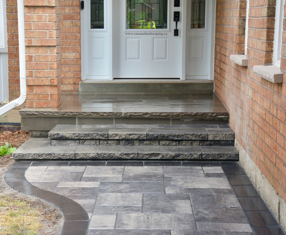 Front entrance of a brick house with steps and a stone pathway.