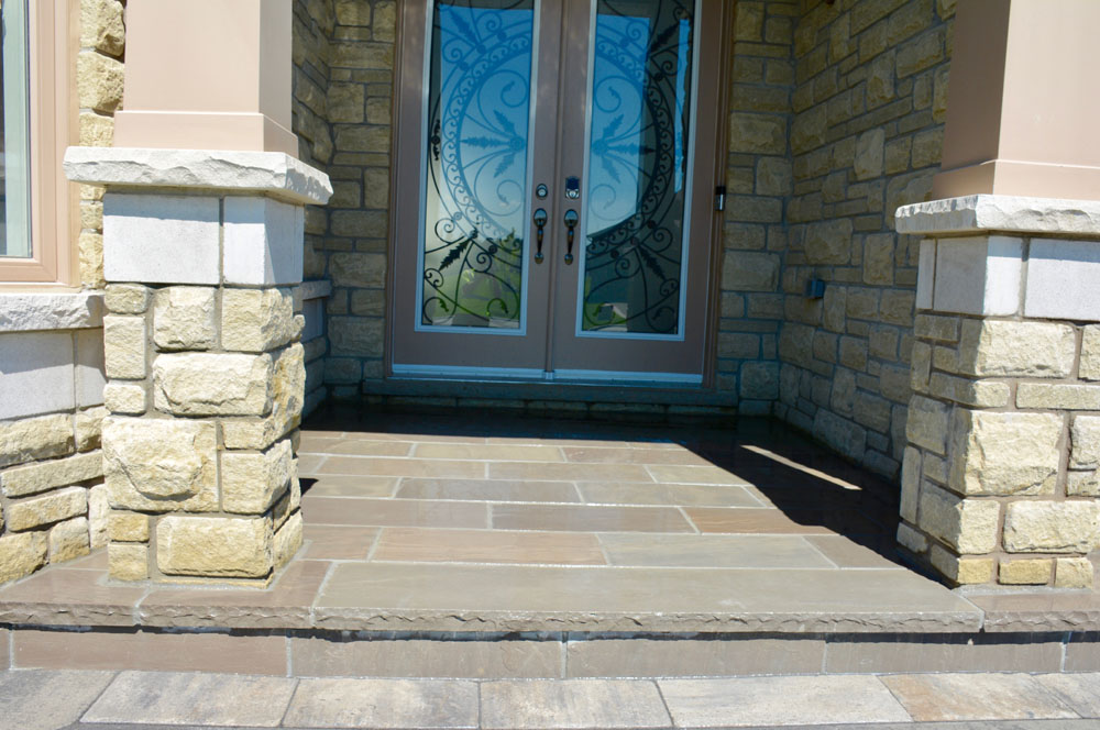 Stone doorway entrance with decorative glass doors and brick columns