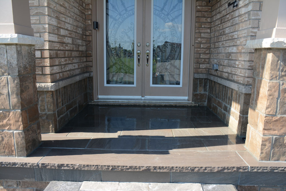 Front porch with a double door entrance, brick walls, and stone steps.
