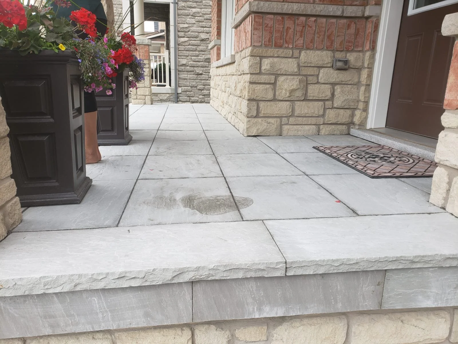 Stone porch with flower pots and welcome mat
