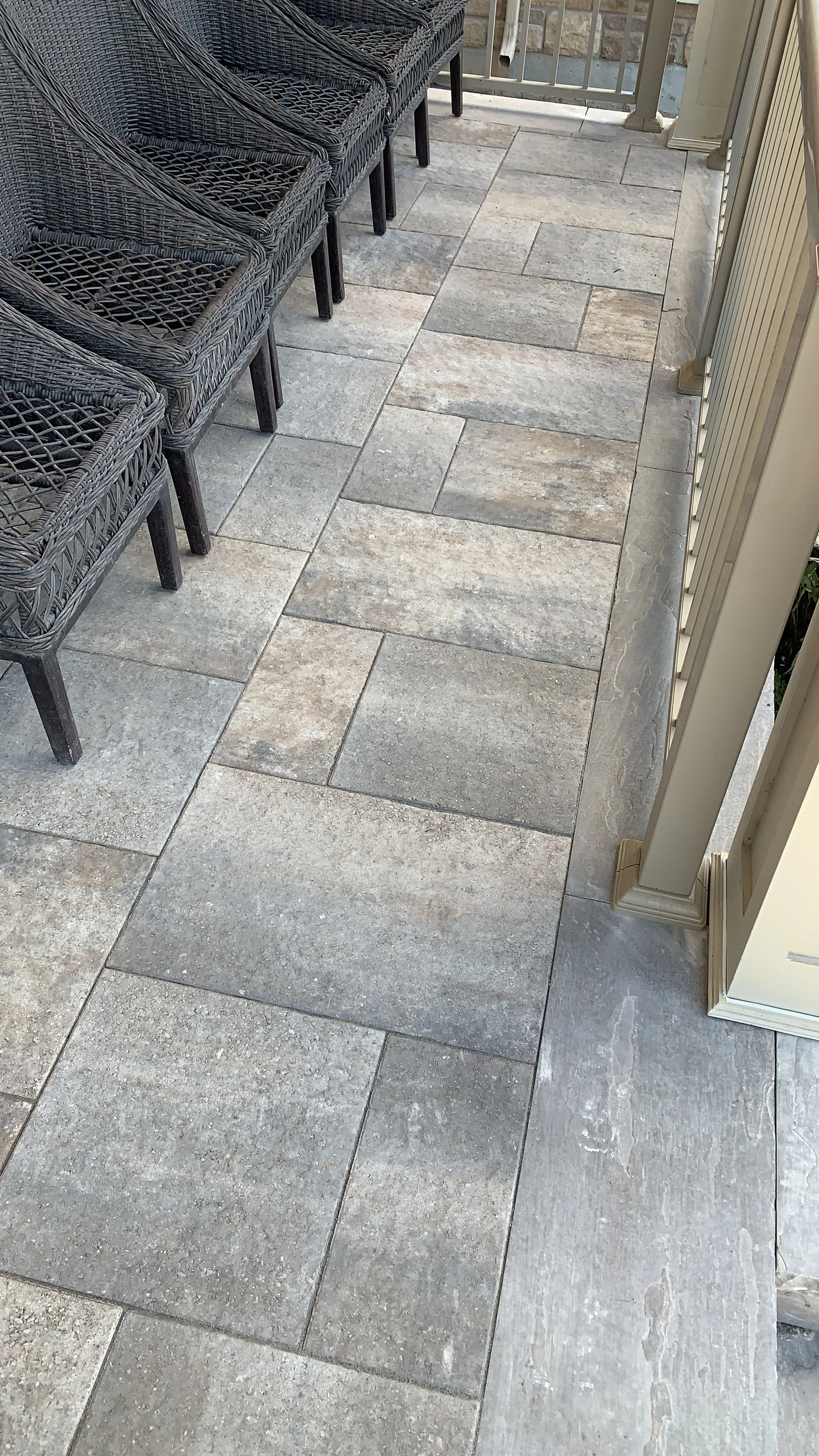 Gray tiled floor with wicker chairs along a porch railing
