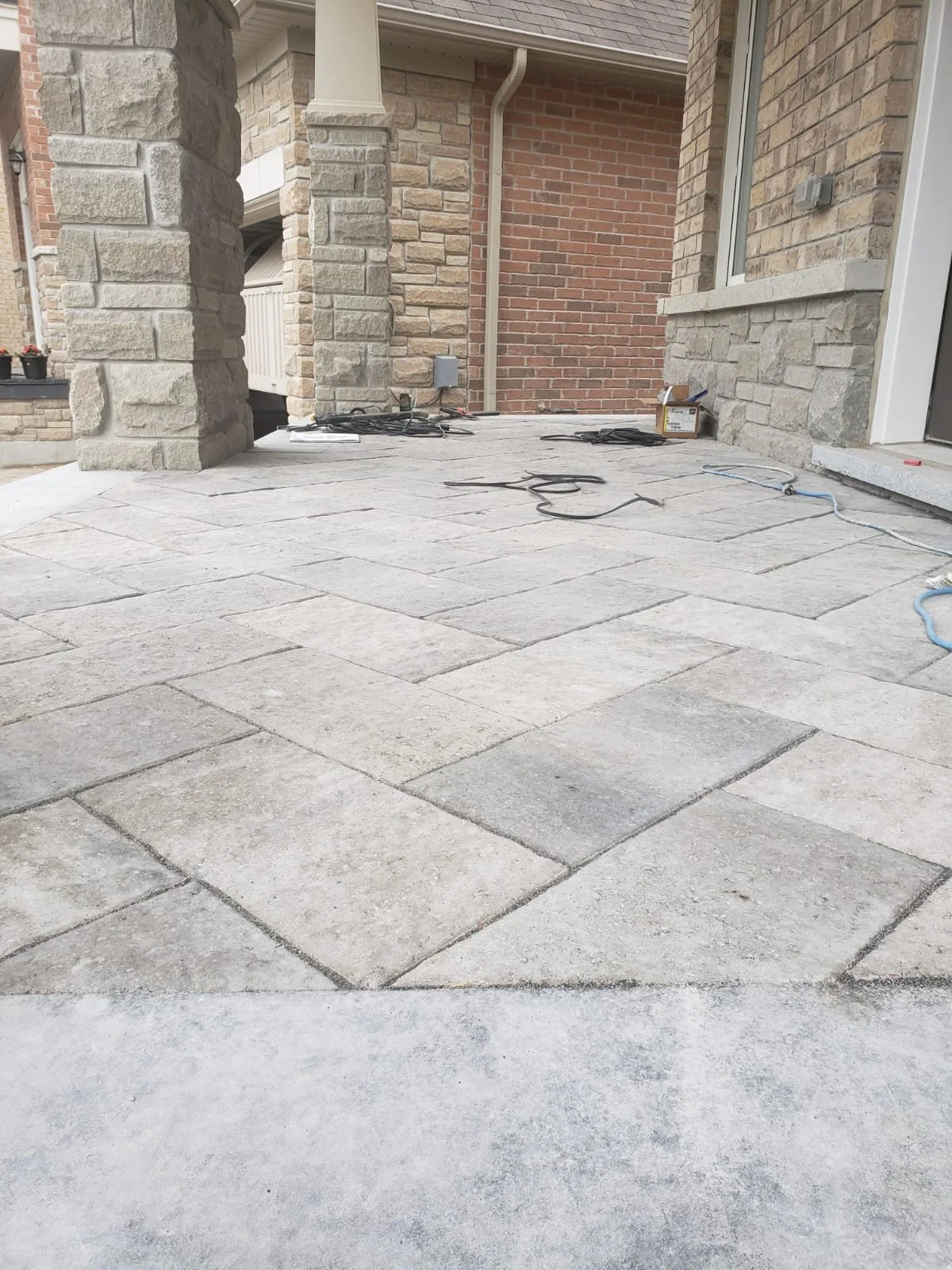 Stone patio with brick and stone walls, featuring scattered wires and tools on the ground.
