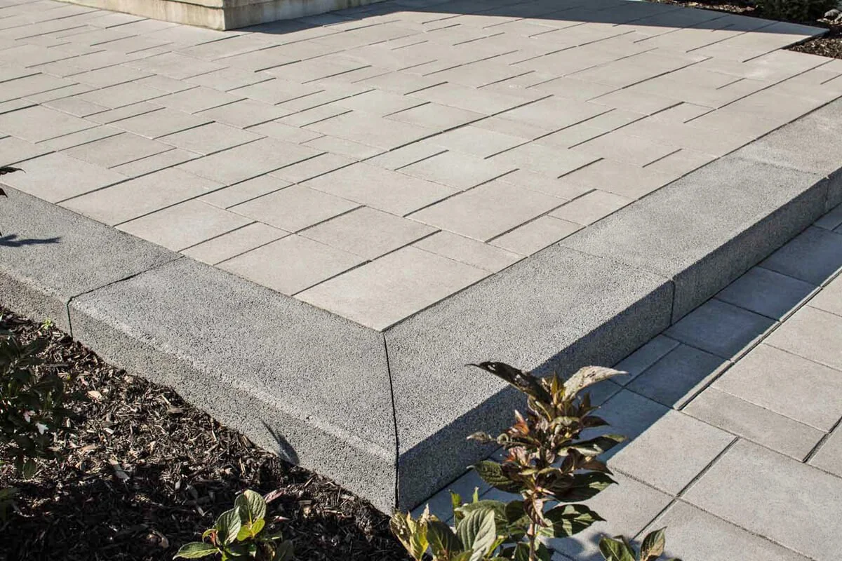 Concrete paver patio with a raised edge and plants nearby