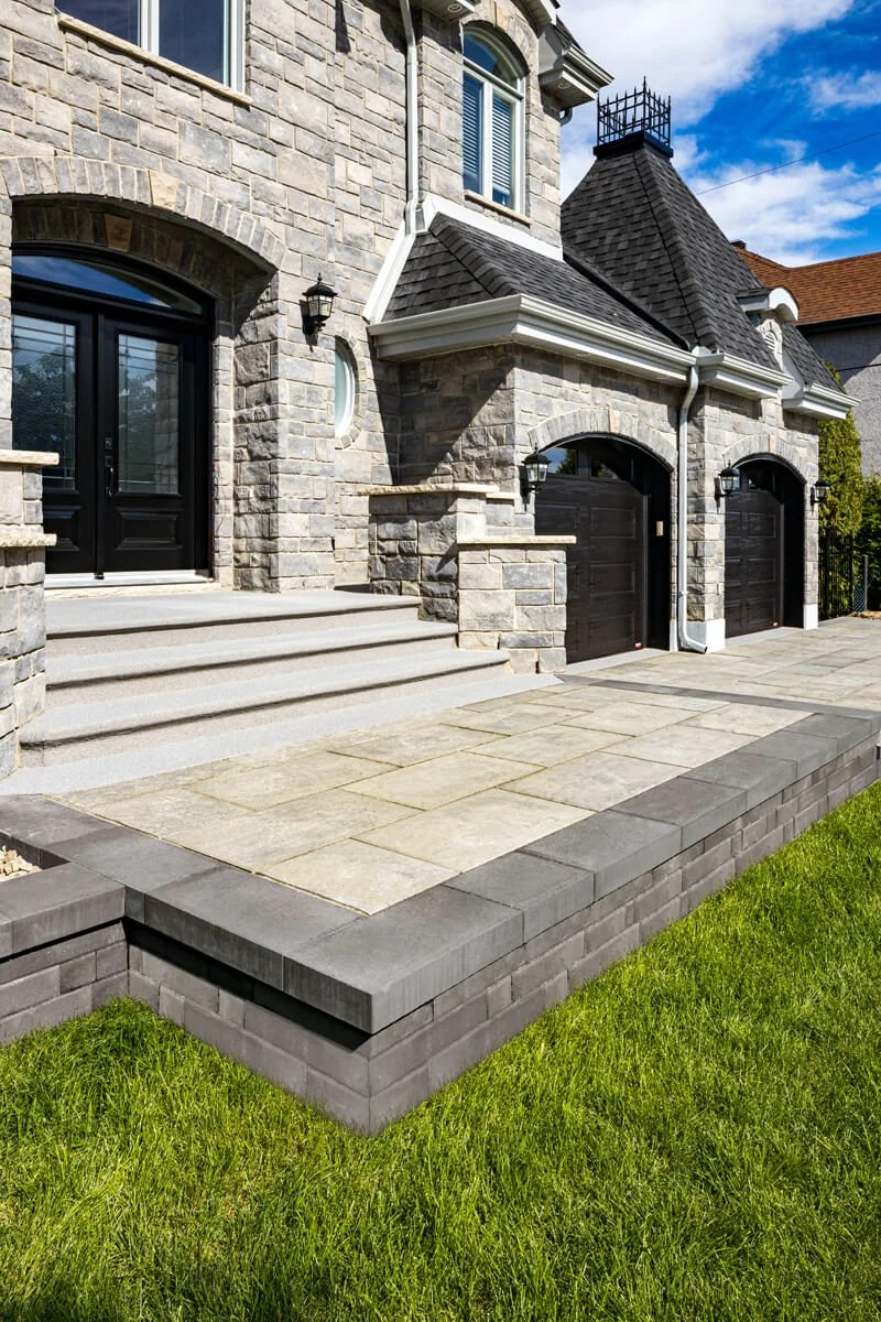 Stone house facade with black doors, a patio, and green lawn.