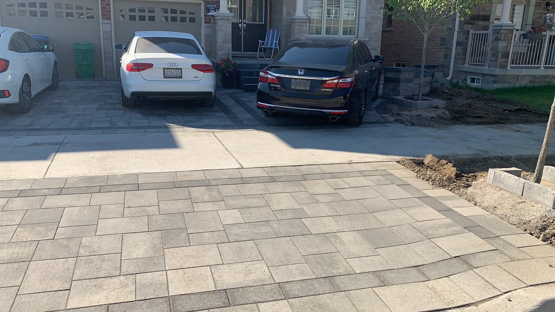 Cars parked in a residential driveway with brick paving.