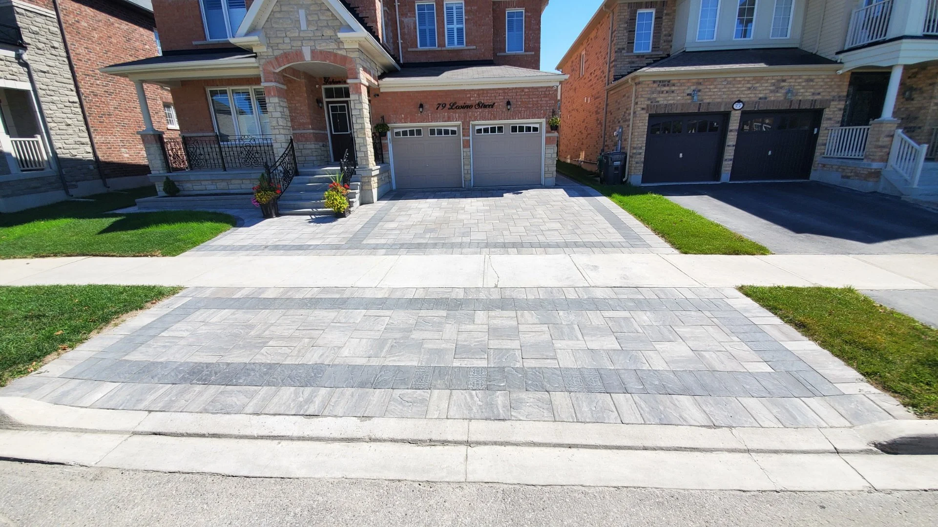 Front view of a suburban house with a brick facade, two-car garage, paved driveway, and small front lawn.
