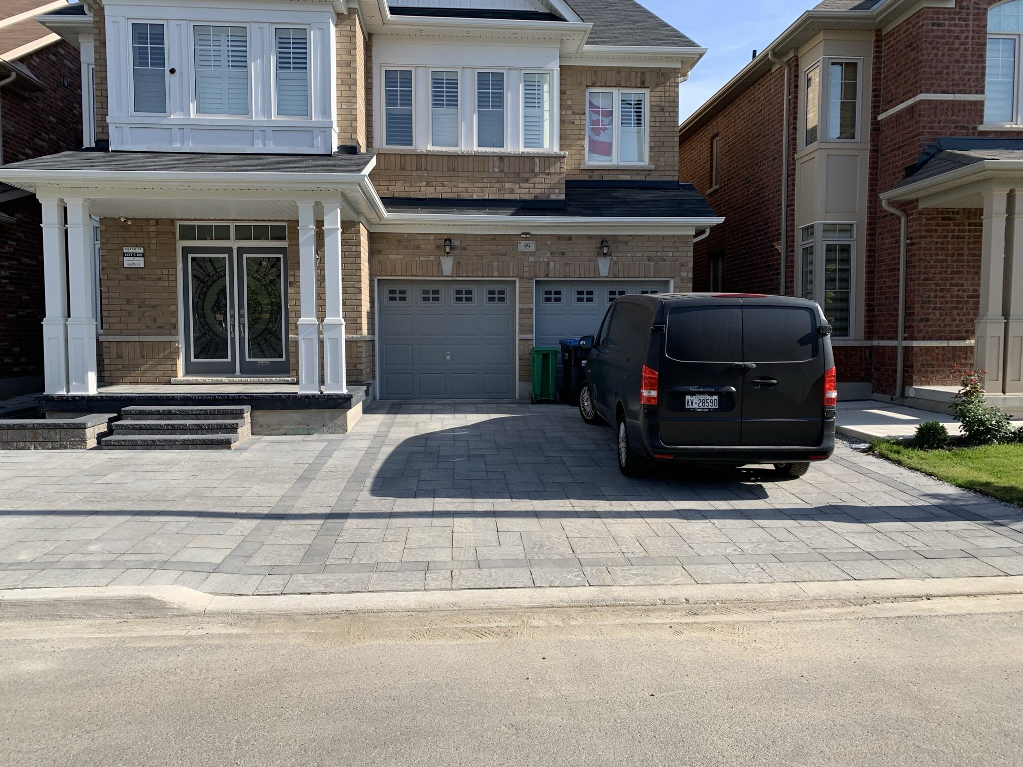 Two-story suburban house with a double garage and a black van parked in the driveway.