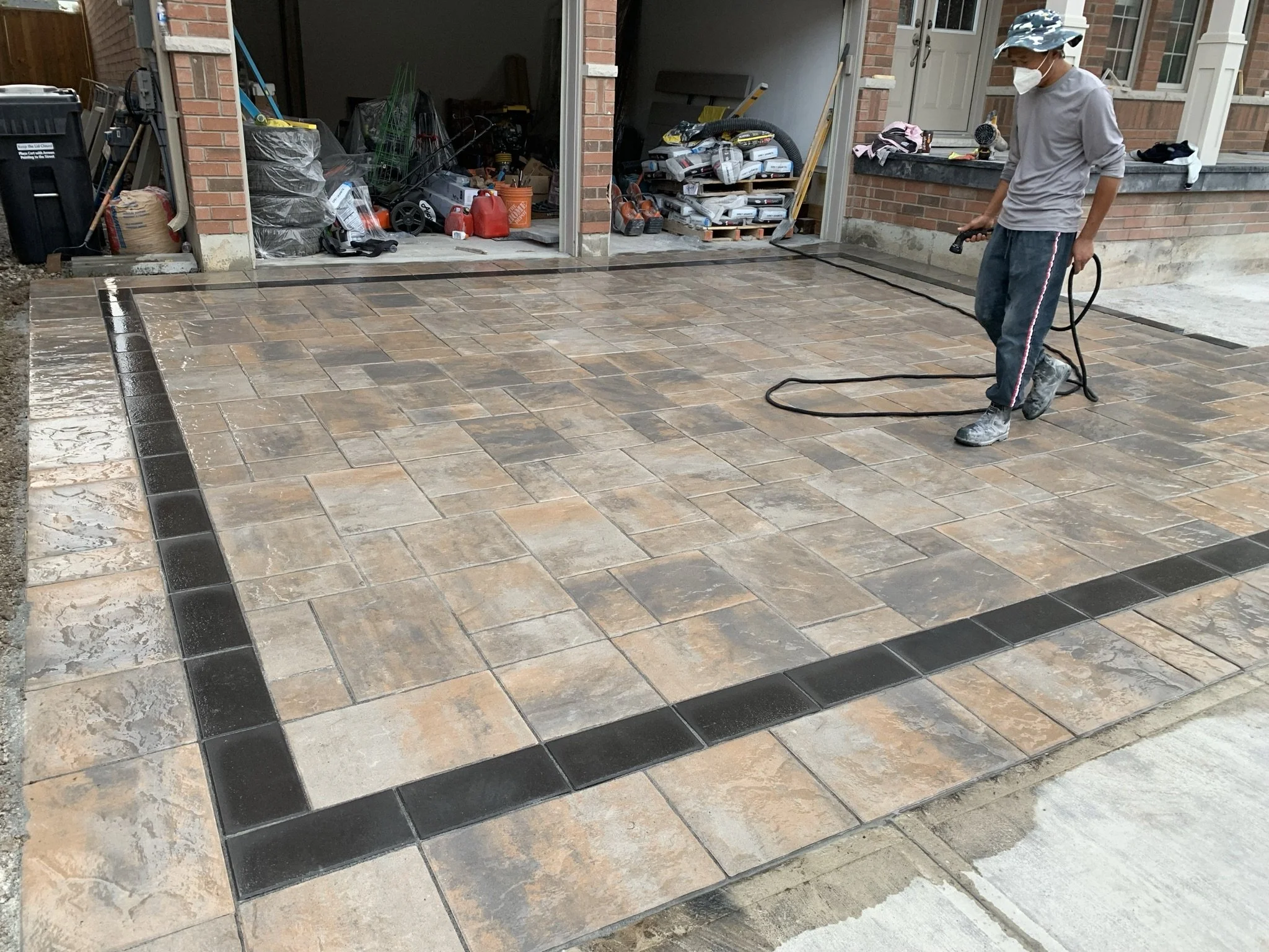 Person cleaning newly installed patio with tile flooring using a hose
