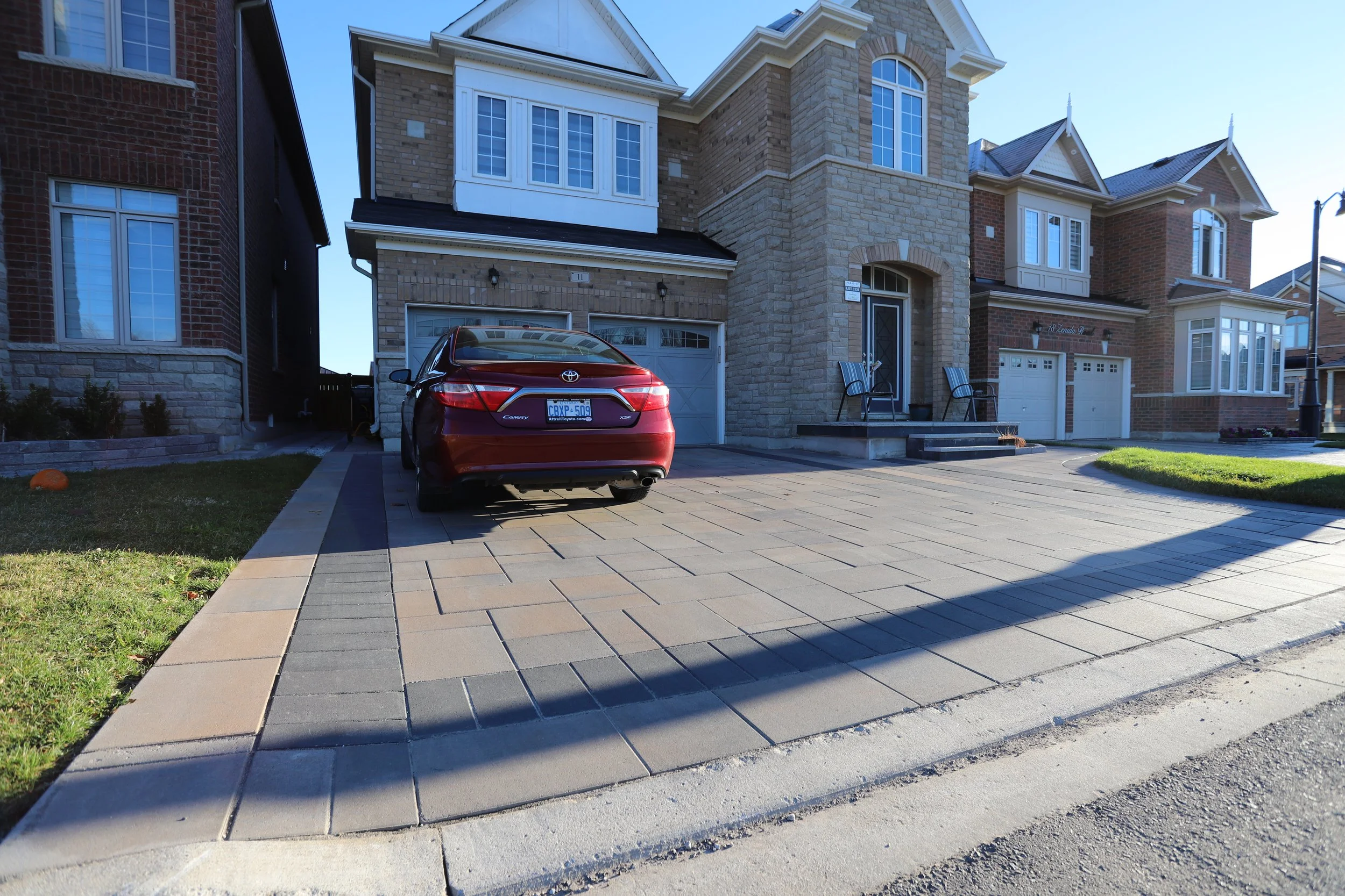 Residential driveway with a parked red car in front of a brick house