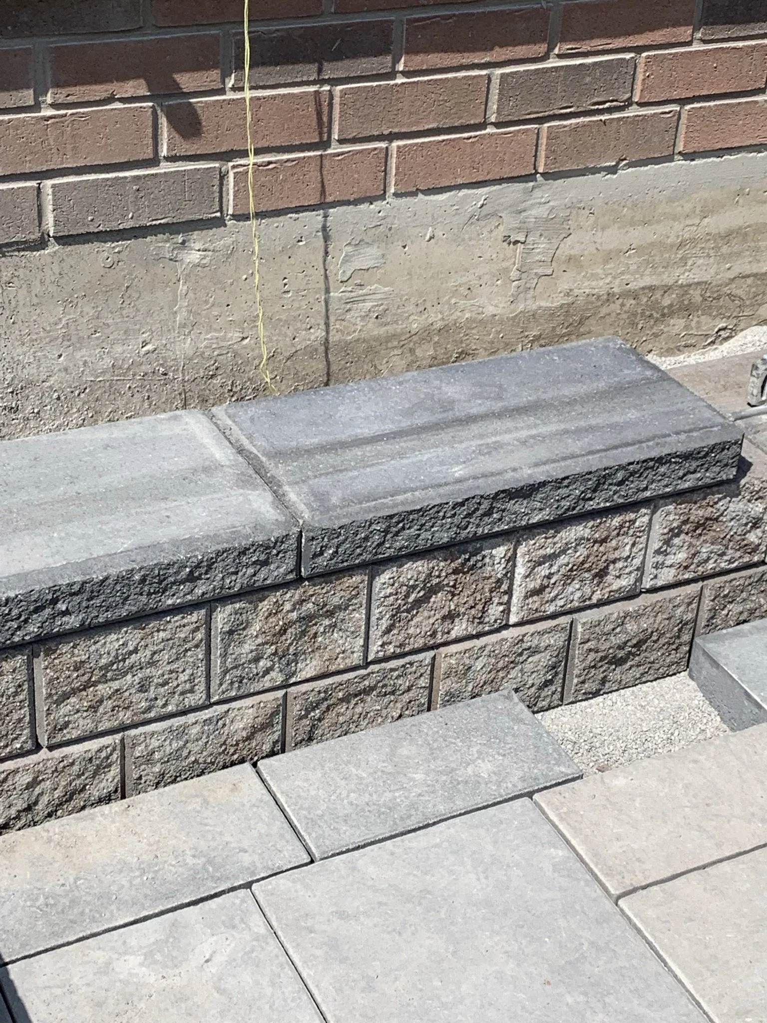 Close-up of a brick wall with newly constructed stone steps and a level string line.