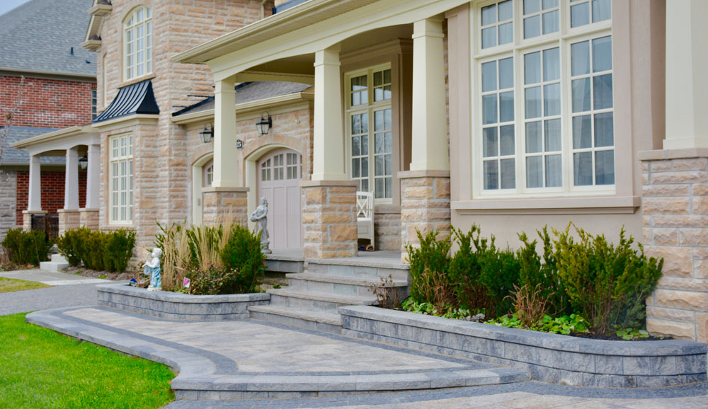 Front view of a luxury brick house with large windows and a landscaped garden.