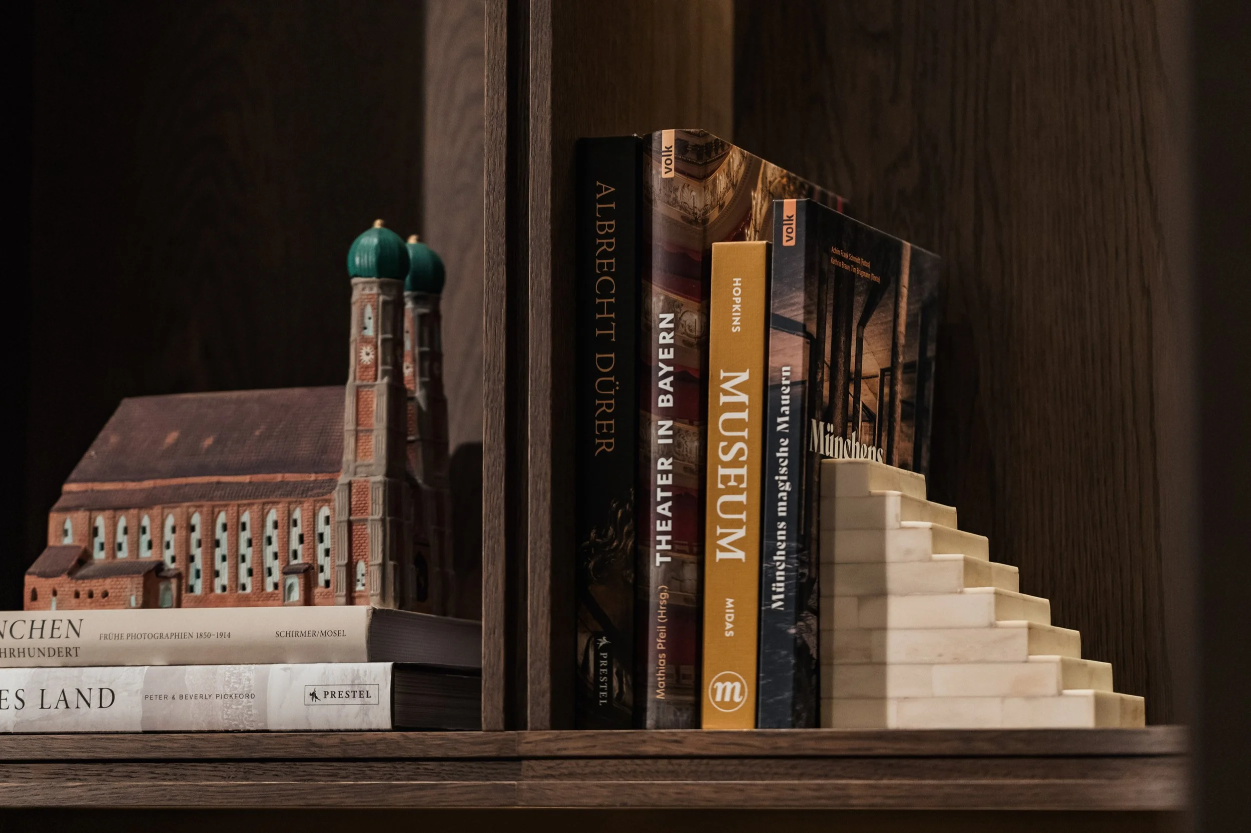 Books on a dark wooden shelf, including titles about architecture, history, and travel.