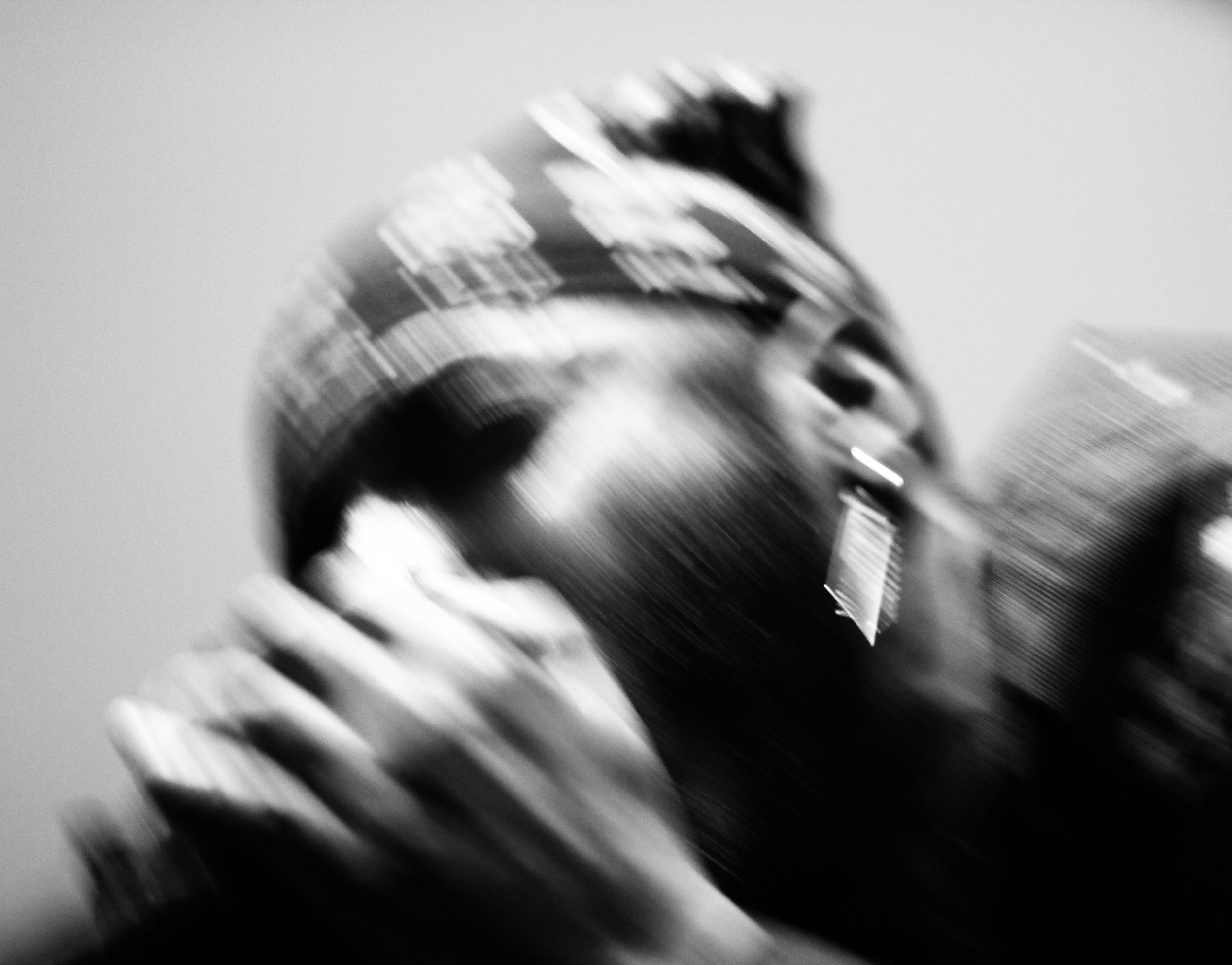 A blurred black and silver object with a textured grip and a rounded top, possibly a metal tool or part of a mechanical device, against a light background.