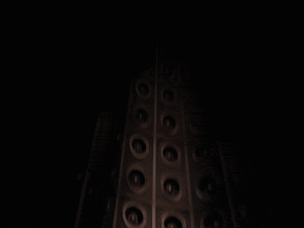 A large speaker tower with multiple cone speakers stacked vertically, seen from below against a dark background.